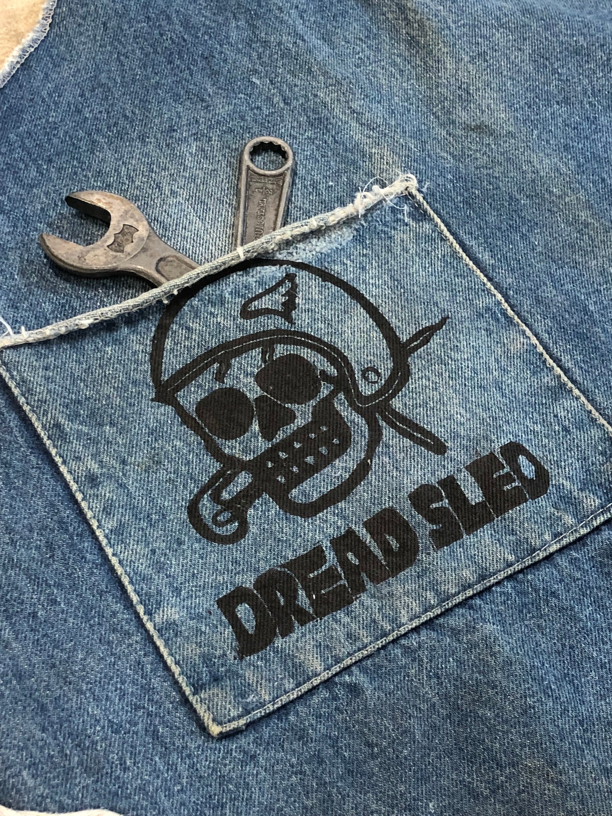 Denim patch with a logo and wrench on a denim background